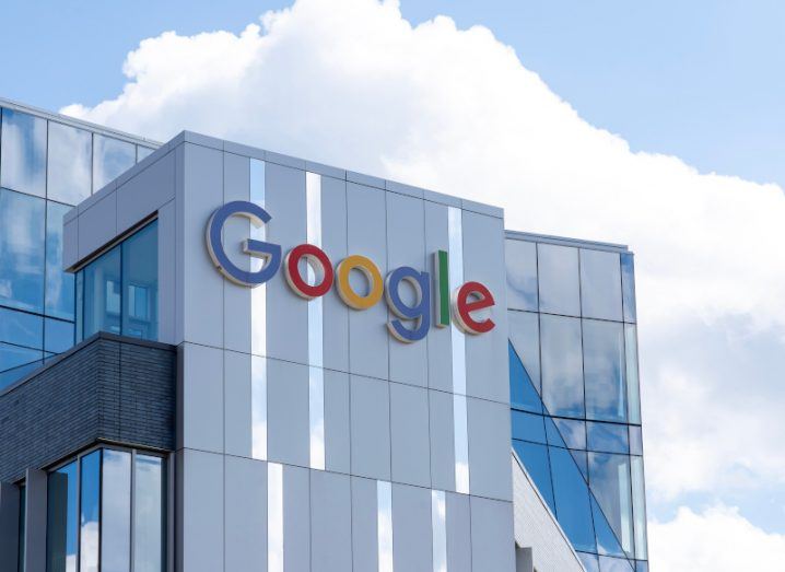 The Google logo on the side of a windowed building, with a blue sky and l