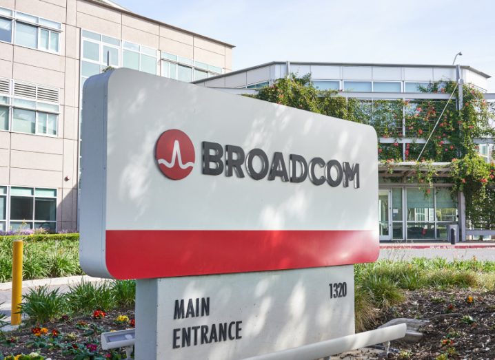 The Broadcom logo on a sign outside a building, with grass and soil on the ground around the sign.
