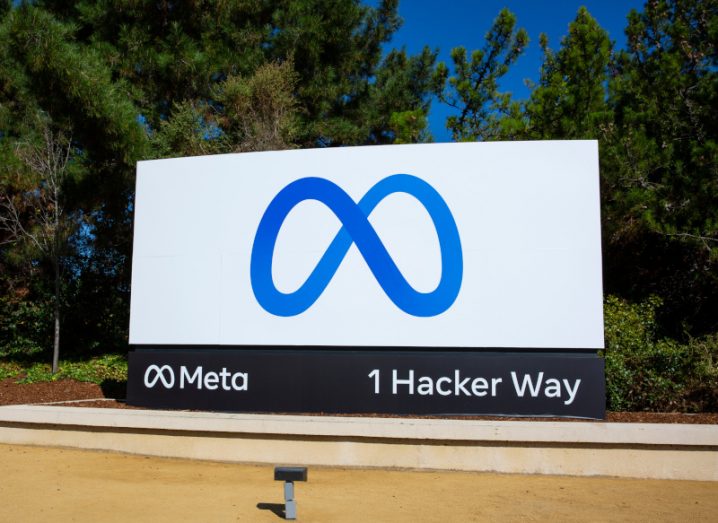 Meta company logo on a billboard, with trees and a blue sky in the background.