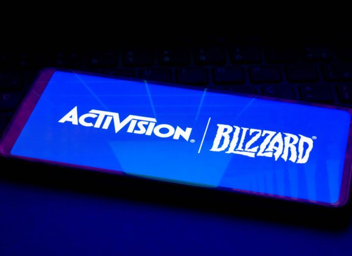 An Activision Blizzard logo on the screen of a smartphone that is resting on a keyboard. The company is in a deal to be acquired by Microsoft.