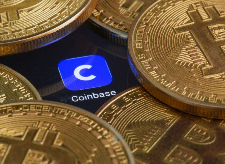 A close-up of the Coinbase app on a screen, surrounded by bitcoins.