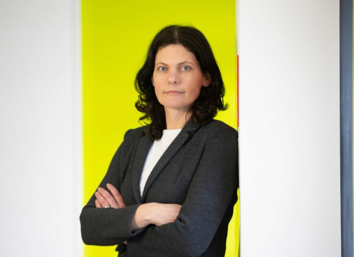 Dr Deidre Kilbane, Walton Institute, headshot of her standing against a yellow and white set of walls.