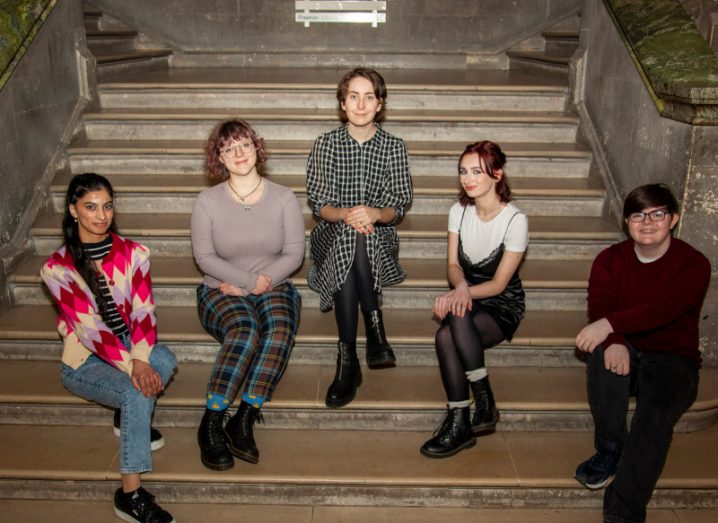 Five women sitting together on stairs in Trinity College Dublin.
