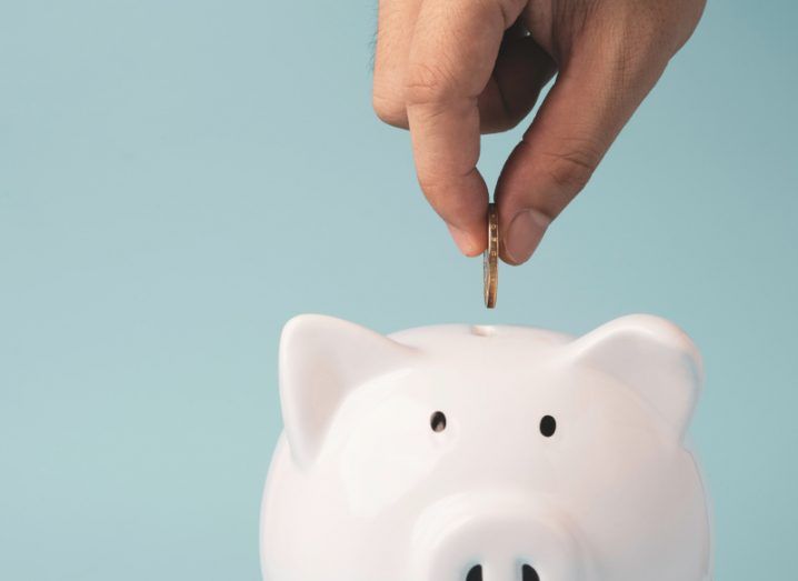 Image of someone dropping a coin into a piggy bank. Represents European tech investment.