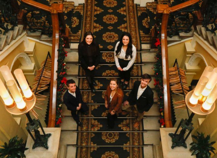 Aerial shot of 5 students from Ireland who won the Huawei scholarship looking up from a staircase in the Royal College of Physicians in Dublin.