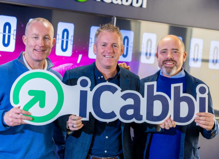 Three men stand holding a sign that says iCabbi.