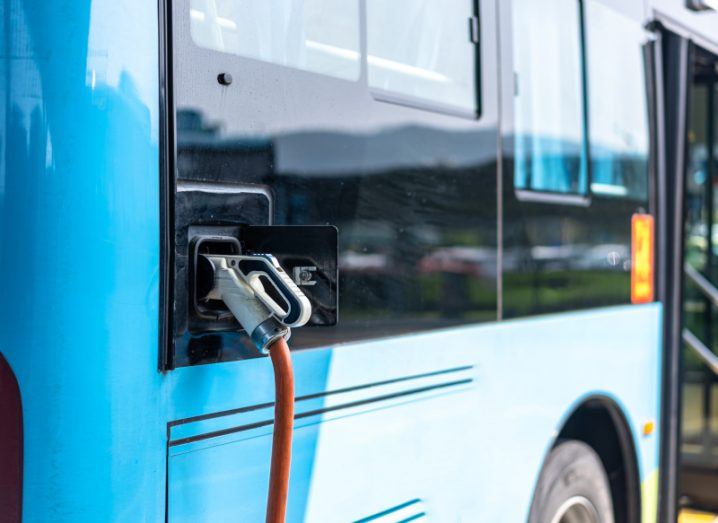 A blue electric bus being charged.