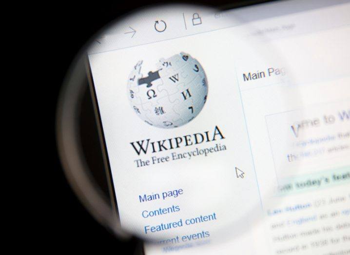 The Wikipedia logo and website, with the logo being focused on through a magnifying glass.