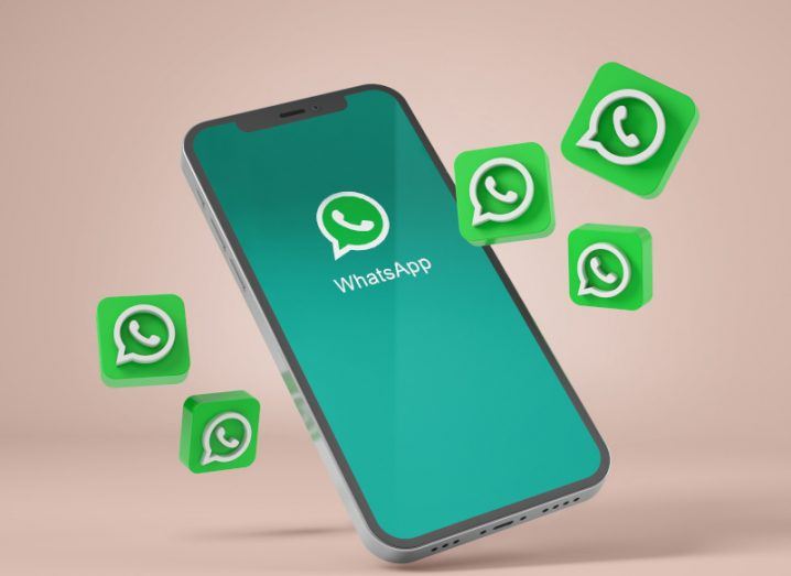 Phone with the WhatsApp logo on it on a green background. There are WhatsApp logos floating in mid-air around the phone.