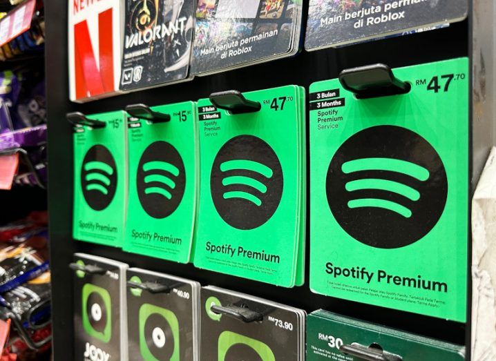 A line of green gift cards for Spotify Premium, on a shelf in a store.