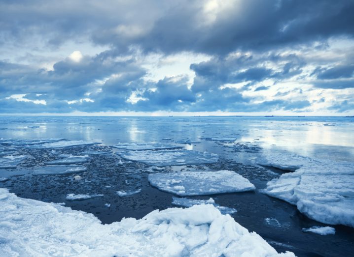 Winter coastal landscape with floating ice fragments on still cold blue water. Gulf of Finland, Russia