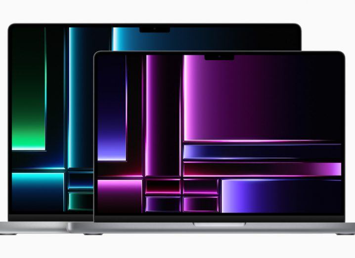 Two open MacBook Pro laptops on a white background. The larger model has green jewel tones on its display, while the smaller model has purple colouring.
