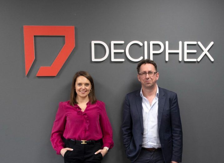 Jennifer McMahon of Seroba and Dr Donal O'Shea of Deciphex, standing together in front of a dark grey wall with the Deciphex logo above them.