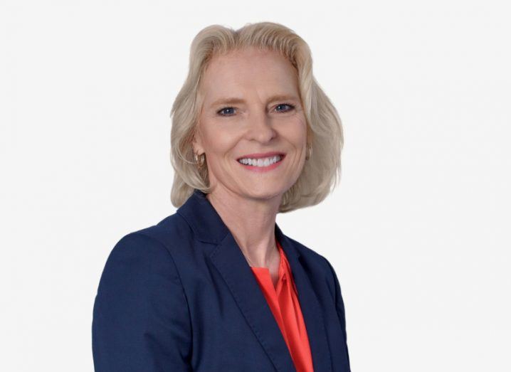 Dr Nicola Hodson of IBM, wearing a navy suit and red top, in a white background.