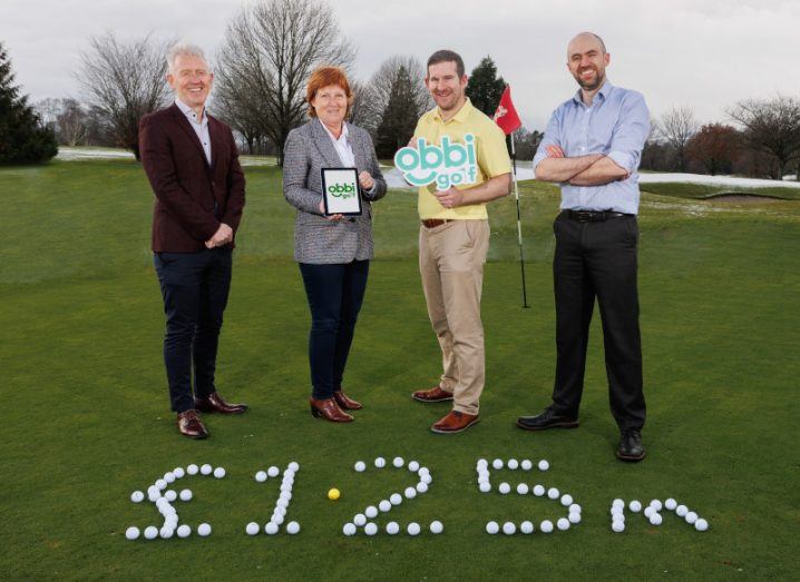 Four people standing on a golf green celebrating Obbi Golf's funding news. The amount of 1.25m pounds is spelled out at their feet in golf balls.