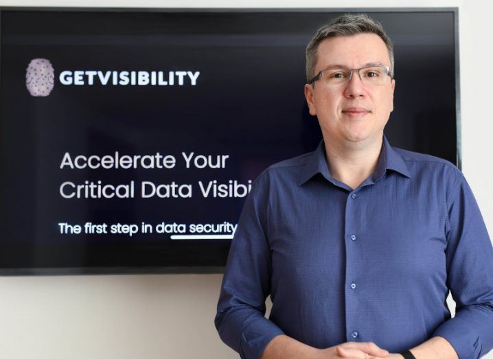 Vlad Constantinescu of Getvisibility standing in front of a wall. The wall has a black sign on it with the Getvisibility logo.