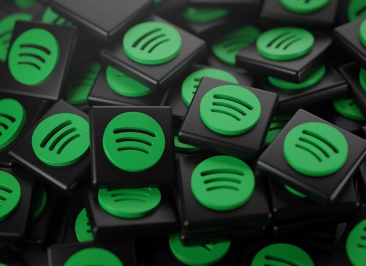 Pile of 3D Spotify Logos that are green on black tiles.