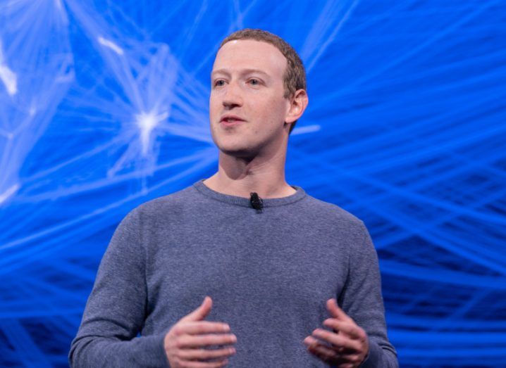 Meta CEO Mark Zuckerberg standing on a stage with a blue background.