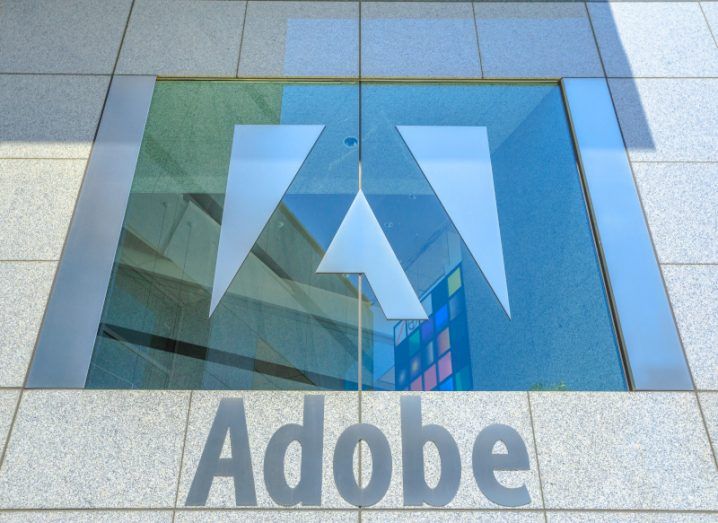 The Adobe logo on the window of a building, with the company name on a building wall under the window.