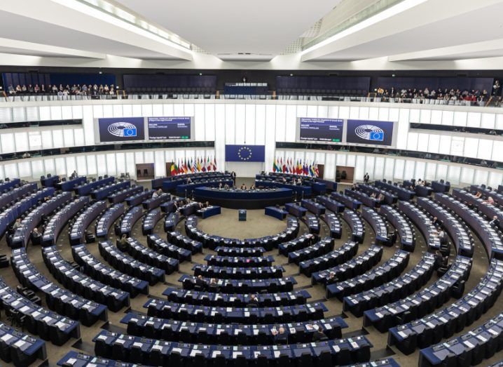 Interior of the European Parliament in Strasbourg, with rows of seats and an EU flag visible in the centre of the room.