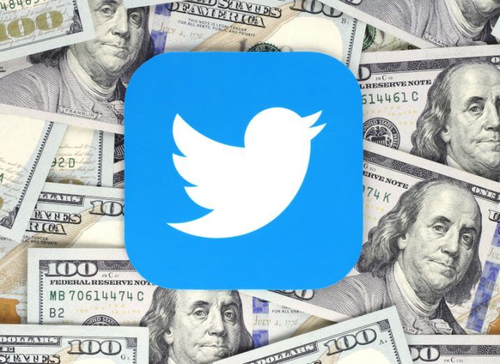 The Twitter logo icon on a scattered pile of US dollar bills.