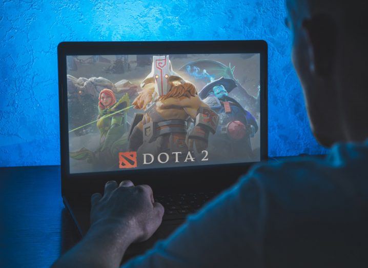 A person on a laptop with the Dota 2 logo on the screen.