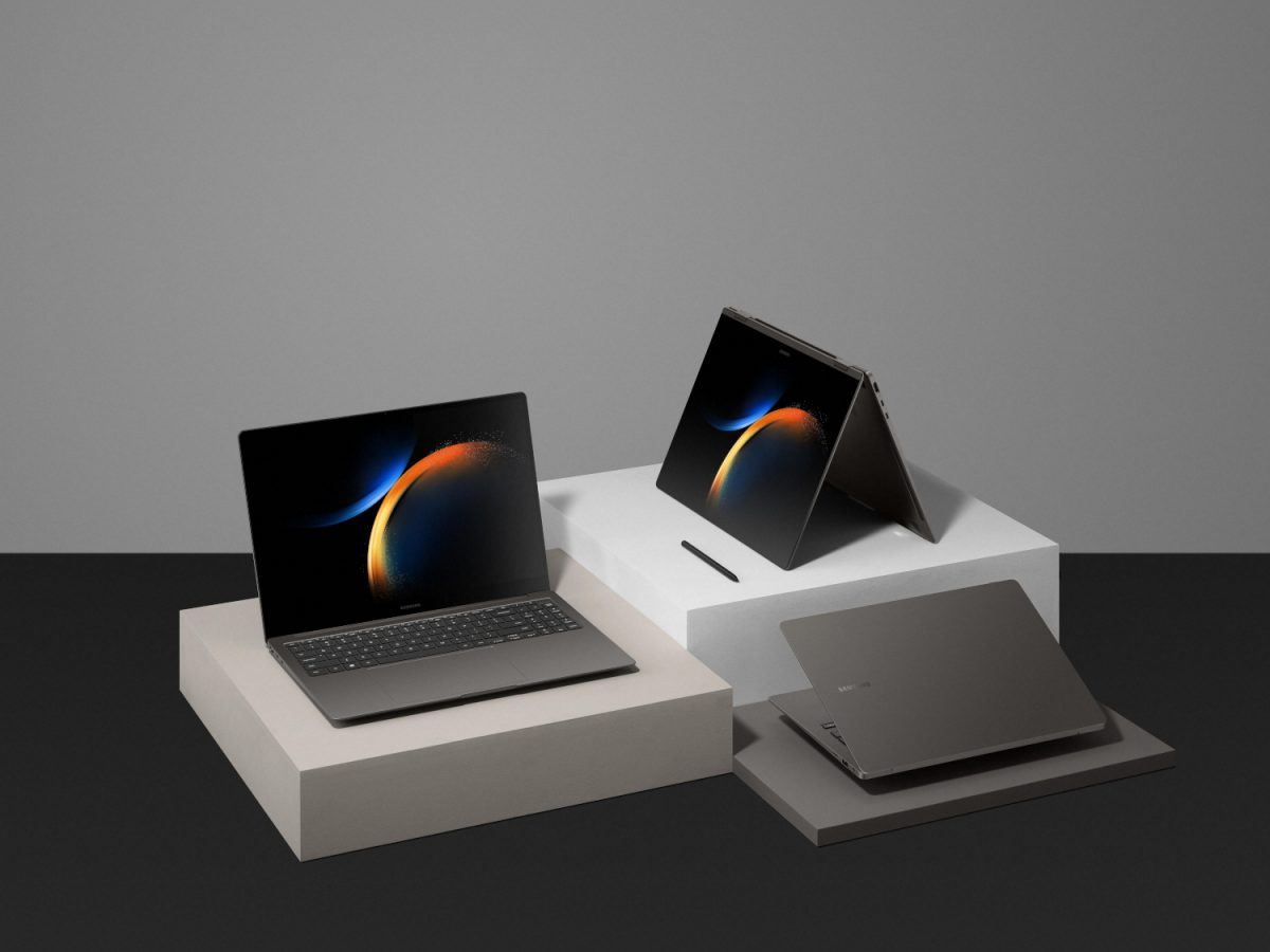 Three Samsung Galaxy laptops, laying on separate grey squares on a dark surface and a dark grey background.