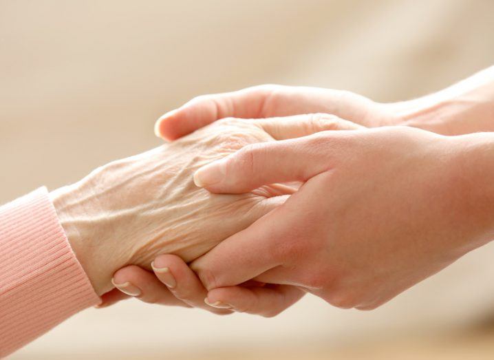 Photo of a pair of hands holding an elderly person's hand.