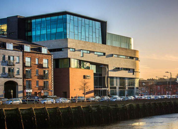 The MTU School of Music in Cork, with a river in front of it and a sunset sky in the background.