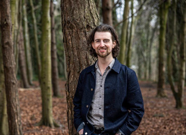 A man standing in the woods with trees in the background. He is Refurbed marketing manager for Ireland, Pádraig Power.