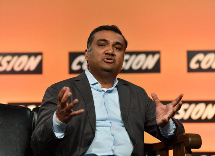 A man speaking on a stage with an orange wall in the background. He is YouTube CEO Neal Mohan.