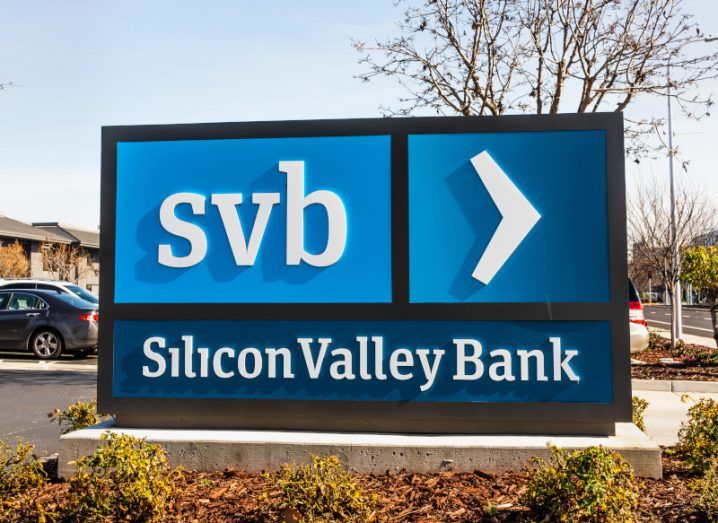 The Silicon Valley Bank logo in front of a small car park, with a tree and a blue sky in the background.