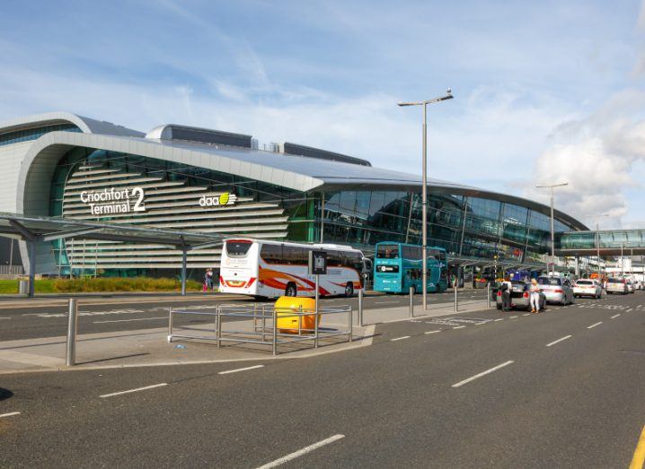 Terminal 2 of Dublin Airport, with vehicles parked in front and a cloudy sky in the background.