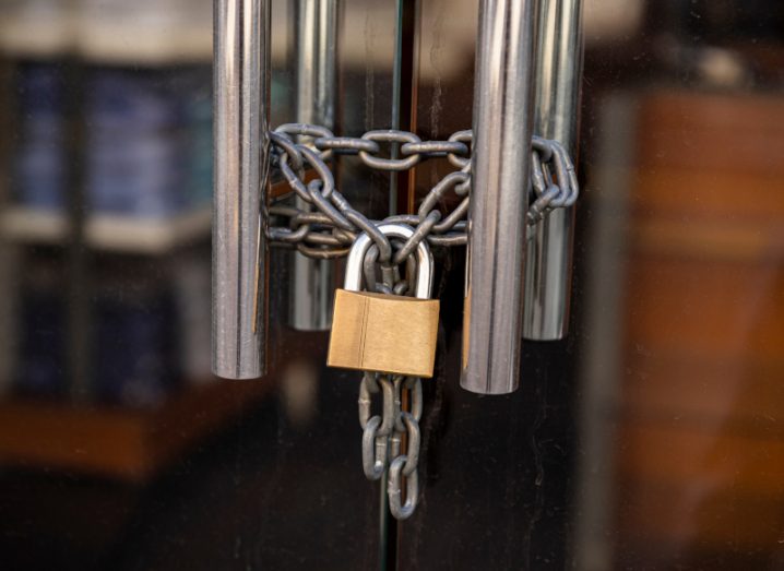 A chain and padlock on the handles of two glass doors.