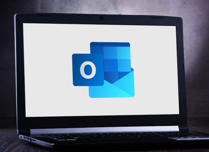 The Outlook logo on a laptop screen, resting on a table.