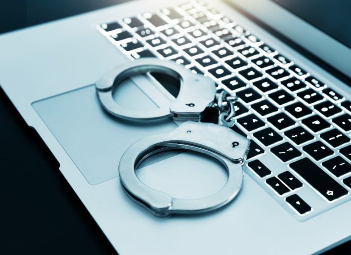 A pair of handcuffs on top of a laptop.
