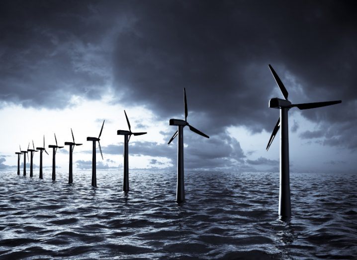 Offshore wind farm with wind turbines at sea under storm clouds.