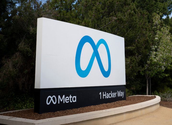 The Meta logo on an entrance with trees in the background.