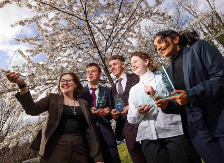 Five teenagers standing under a cherry blossom tree celebrating winning the BT business bootcamp.