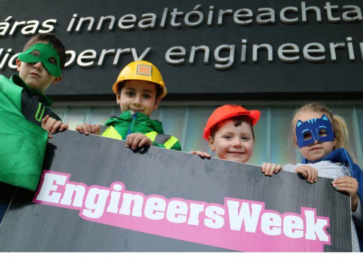 Four children dressed up in costume holding an Engineers Week banner outside University of Galway's engineering building.