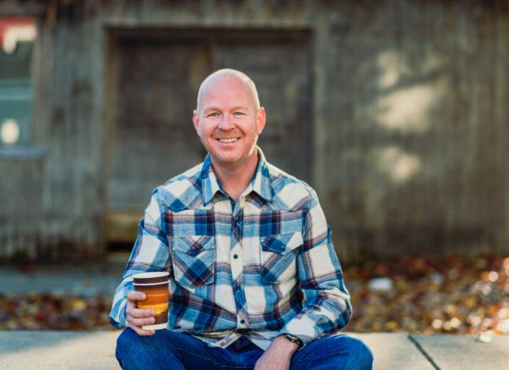 Image of Responsible founder Mark Dowds, sitting while holdin a cup in his right hand, with a wall in the background.