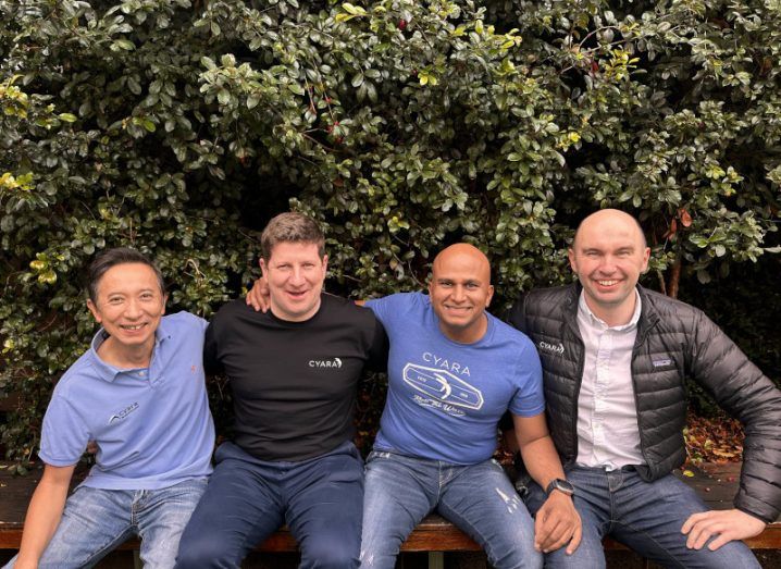 Four men sitting together on a bench, with green plants behind them. They are the co-founders of Spearline and Cyara.