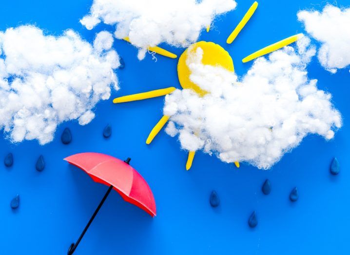 Weather forecast concept. Sunny and rainy, blue background with clouds and a red umbrella.