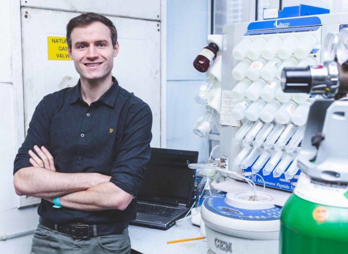 Headshot of Dr Stephen Cochrane with his arms folded across his chest, standing in what looks like a research lab.