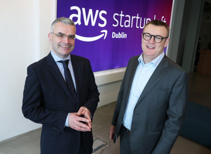 Headshot of two men standing next to each other in business formals. Poster behind them reads AWS Startup Loft Dublin.