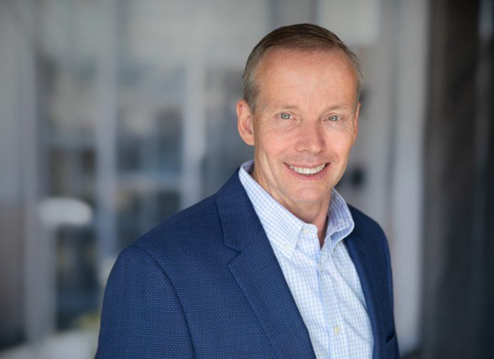 Headshot of Dell CFO Tom Sweet, wearing a suit with windows in the background.