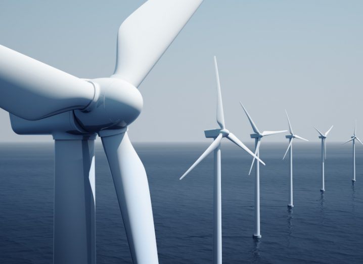 Close up of a wind turbine with other offshore wind turbines visible in the sea behind.