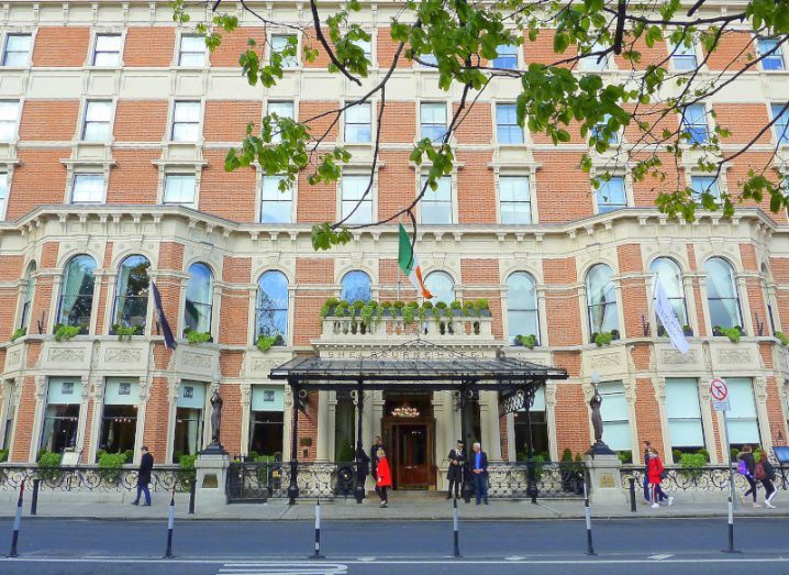 A large building with people in front of it. It is the Shelbourne Hotel in Dublin.