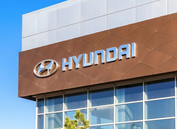 The Hyundai name and logo on the front of a building, with windows below it and a blue sky visible to the left of the building.
