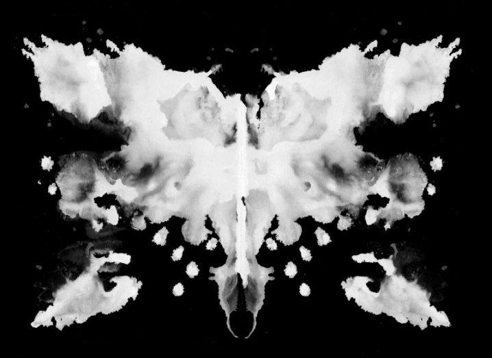 A white Rorschach ink blot test on a dark background.